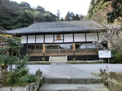行入寺の本堂。木立に囲まれた瓦屋根の堂と石畳の参道