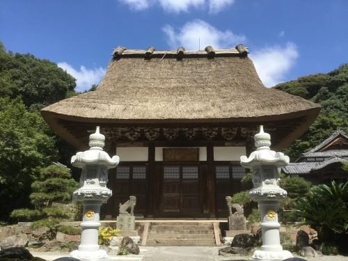 妙徳山泉福寺の茅葺き屋根の本堂（仏殿）と手前に並ぶ一対の石灯籠