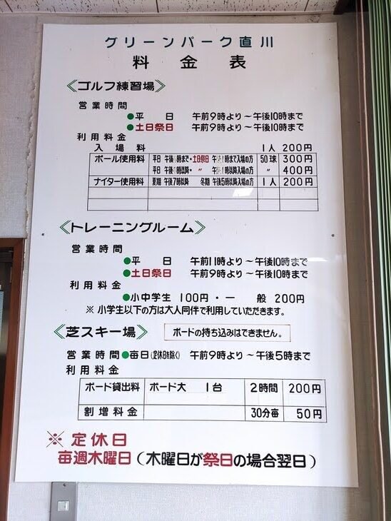 クリーンパーク直川の施設料金案内板。ゴルフ練習場・トレーニングルーム・芝スキー場の営業時間と料金、定休日(毎週木曜)が記されている