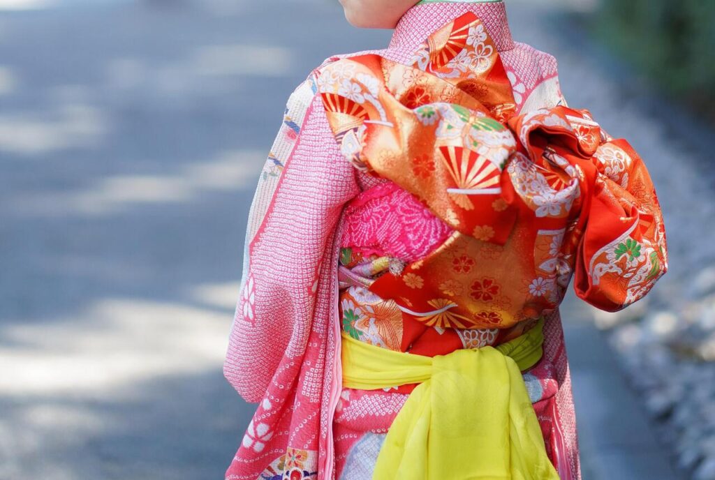 華やかなピンクの縮緬の着物で初詣の参拝をする可愛い子供の後ろ姿