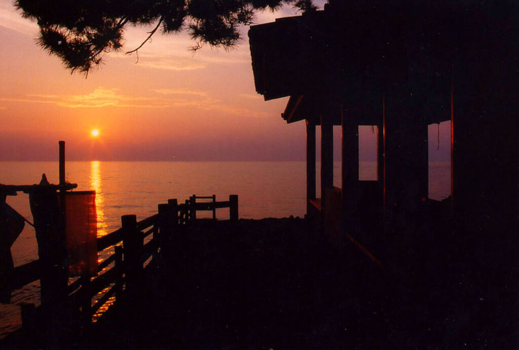 夕日に照らされた粟島神社のシルエット。海に反射する美しい夕景。