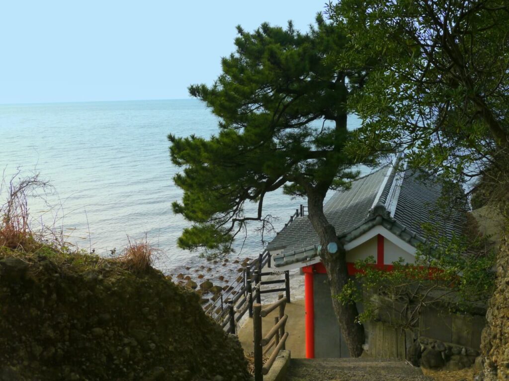 大分県豊後高田市、粟島神社を階段上から撮影。社殿と松の木、奥に広がる海の景色。