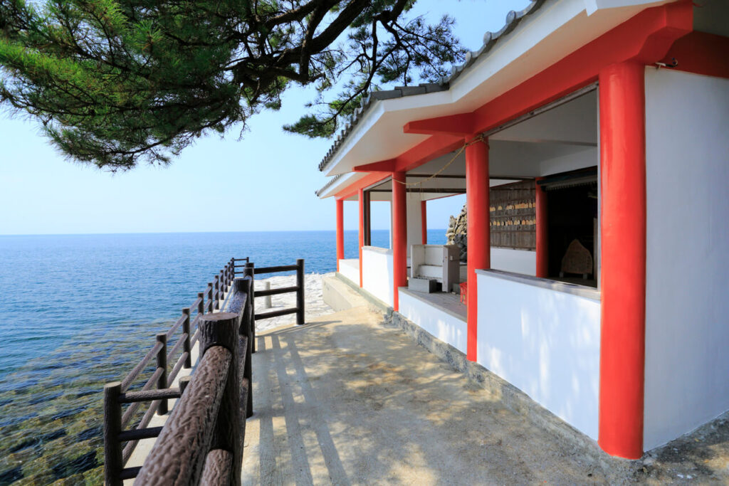 粟島神社の境内を横から撮影した風景。青空と海に囲まれた穏やかな景色。