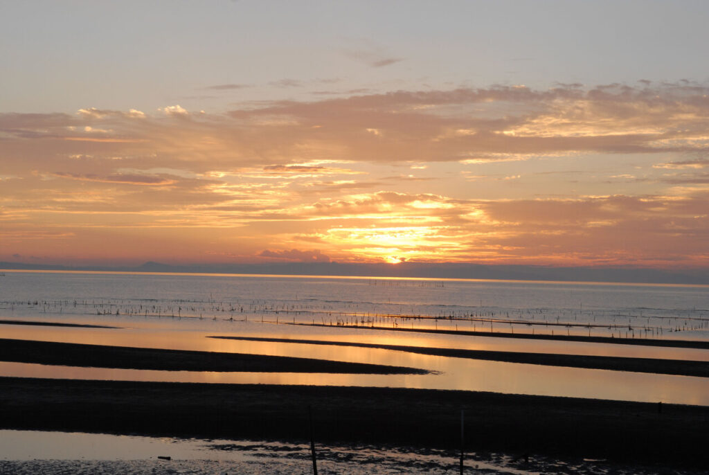 真玉海岸の干潮時の夕景。夕日に照らされた干潟と美しい海の景色。大分県豊後高田市