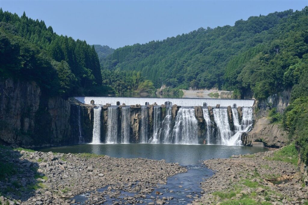 澄んだ青空と豊かな山並みを背景に、正面から一望する登録記念物・沈堕の滝の壮大な引きの構図