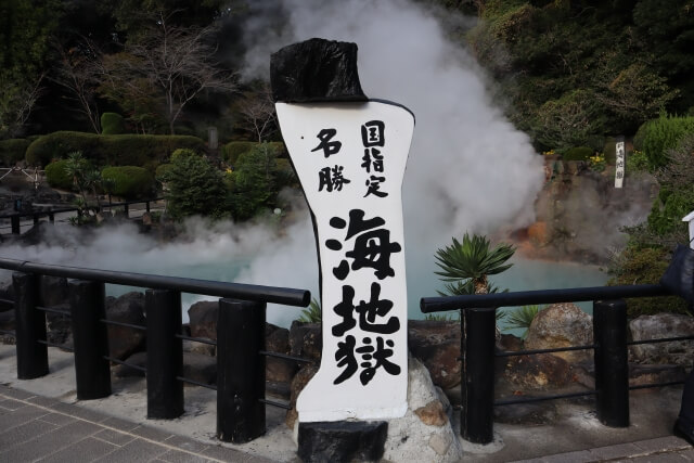 海地獄の立て看板と、その奥に広がるコバルトブルーの湯面