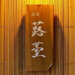 旅庵蕗薹の木製表札のアップ。手書きのような書体で宿の名前が刻まれ、温かみのある雰囲気を伝える