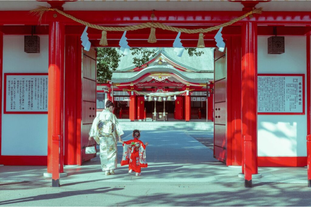 春日神社の鳥居をくぐる着物姿の母と娘（七五三参拝の様子）