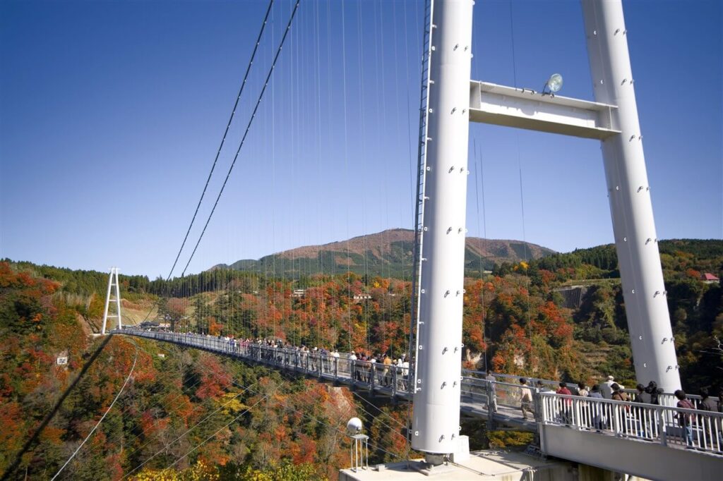 九重町・紅葉に染まる九重“夢”大吊橋を渡る人々。絶景を楽しめる大分の人気スポット