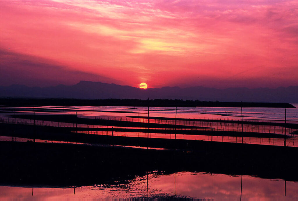 真玉海岸の干潟越しに山へ沈む夕日と日本の夕陽百選の絶景