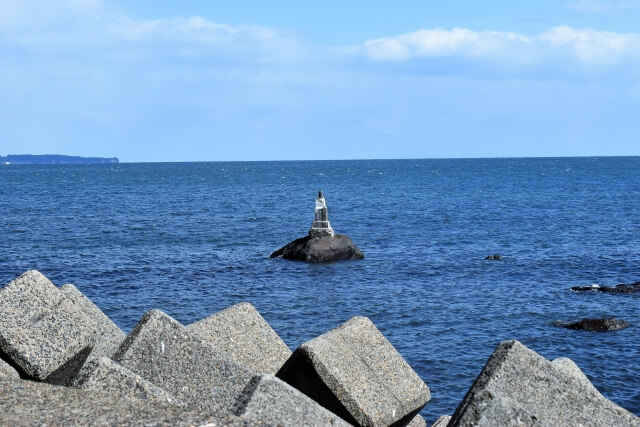 海に浮かぶ岩の上に祀られた石碑が、上人ヶ浜の静けさを引き立てます。