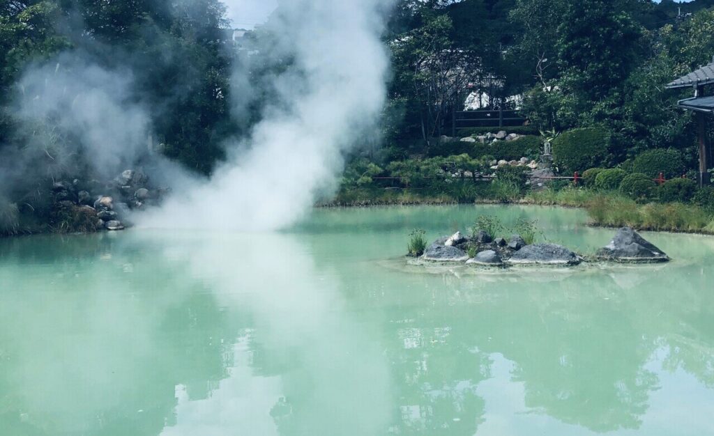 白池地獄の白濁した湯面と周囲の庭園風景