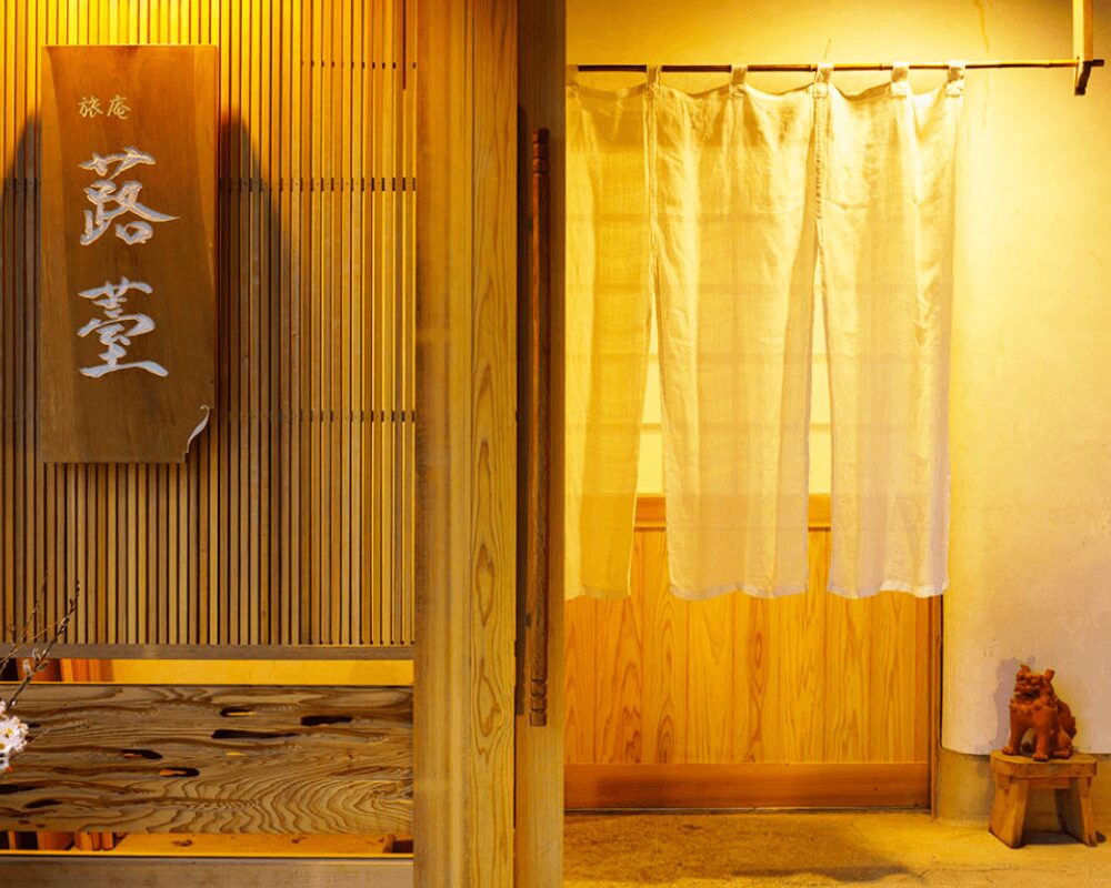 豊後高田市の温泉宿・旅庵 蕗薹の玄関、木の表札と暖簾がかかる入口