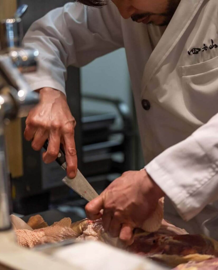 大分県地鶏の店「囲炉裏焼き 四方山」店内の調理場で板前さんの地鶏を捌く様子