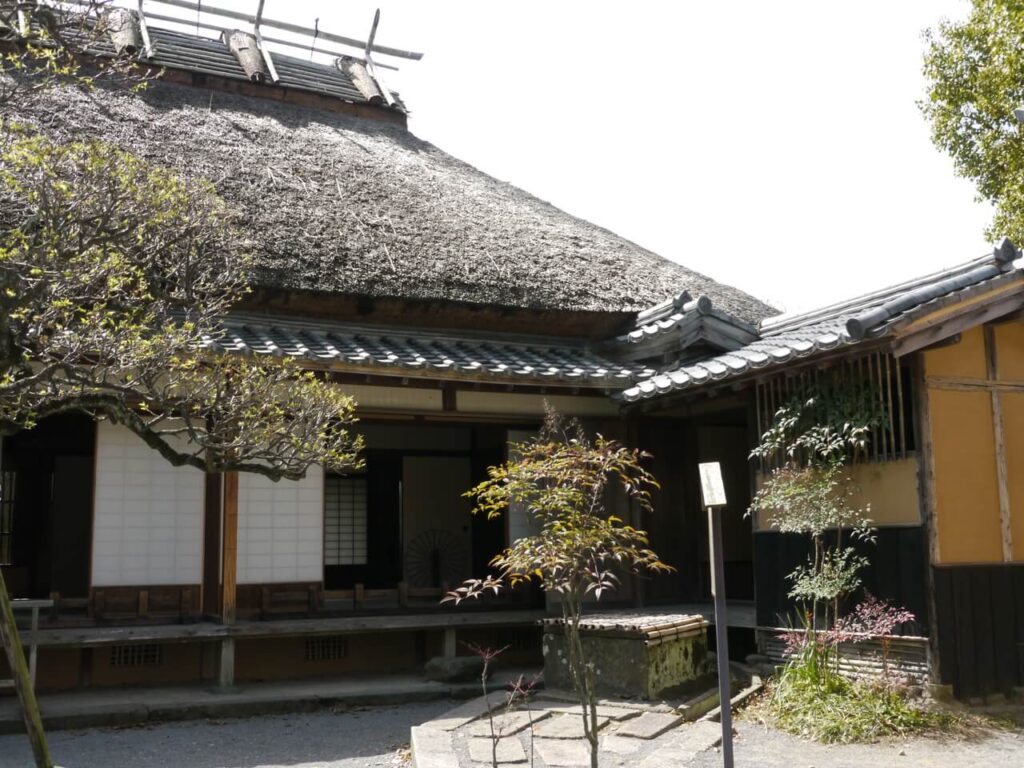 福沢諭吉旧居の庭から室内を望む風景｜茅葺き屋根と当時の暮らしを感じる建物