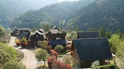 山の斜面に点在するうめキャンプ村のケビン群を見渡す俯瞰写真。秋の紅葉に囲まれた10棟